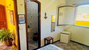 Habitación de hotel con dos camas, una mesita, un espejo, un calentador y una ventana con vistas.