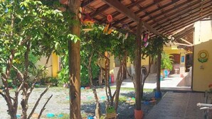 Un espacio al aire libre cubierto, con piso de baldosas, árboles y decoraciones coloridas.