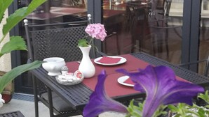 A table set for two with a vase of pink flowers, a white teapot, and a red napkin. - Weinstadt-Hotel (Weinstadt)