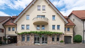 A two-story hotel with a beige facade, a central entrance with a glass balcony, and a red-tiled roof. - Weinstadt-Hotel (Weinstadt)
