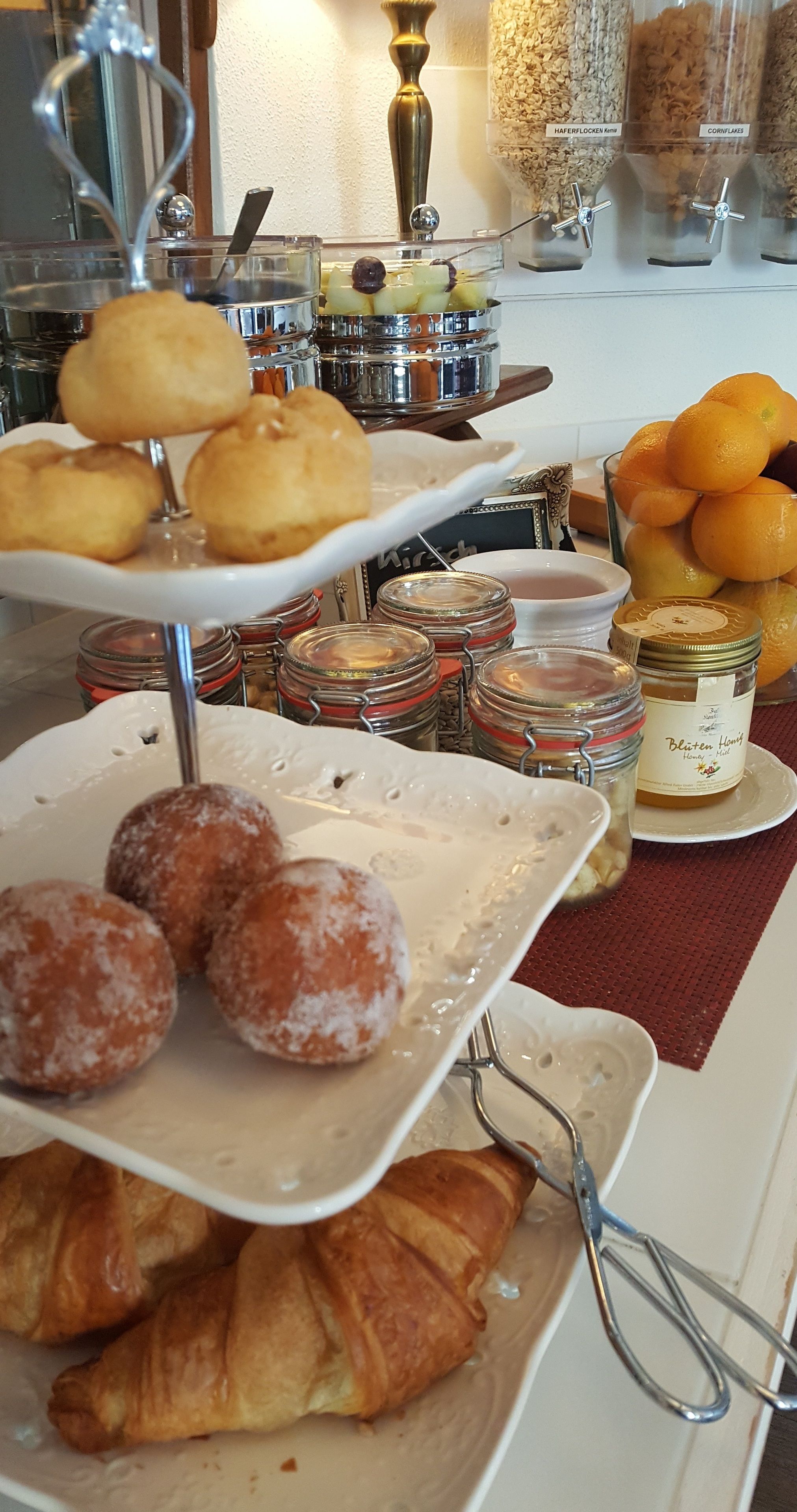 A buffet with pastries, fruits, and condiments.