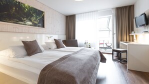 A hotel room with two beds, a desk, a TV, and a large window with curtains. - Weinstadt-Hotel (Weinstadt)