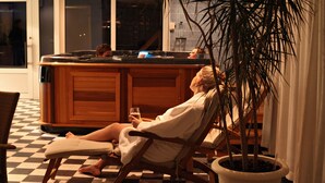 A person relaxing in a chair with a drink, a checkered floor, and a large potted plant. - Sorsele River Hotel (Sorsele)
