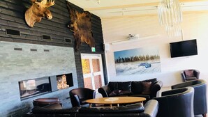 A modern lounge area with leather seating, a fireplace, and a mounted moose head. - Sorsele River Hotel (Sorsele)