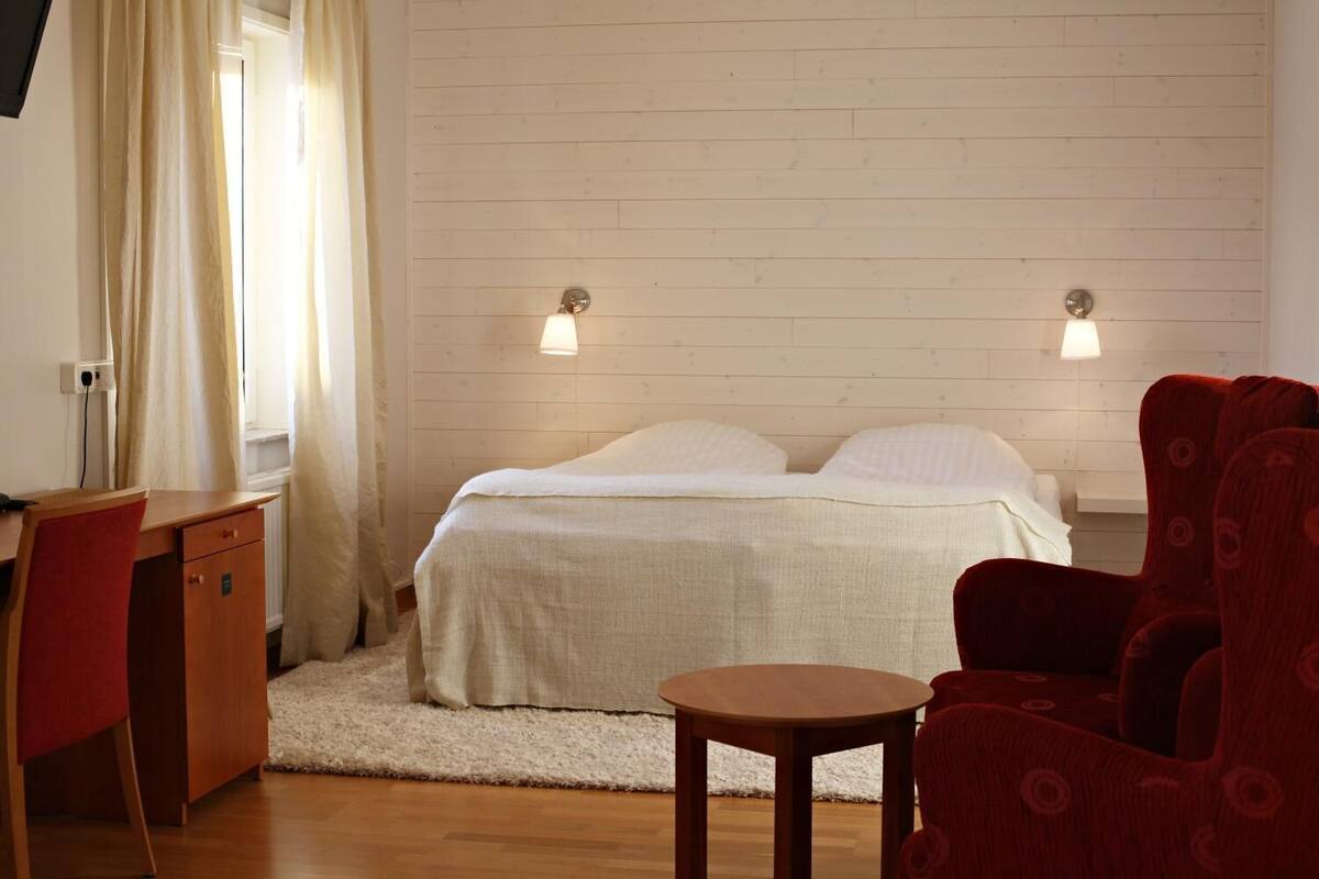 Een slaapkamer met een bed, twee bedlampen, een bureau en een stoel.