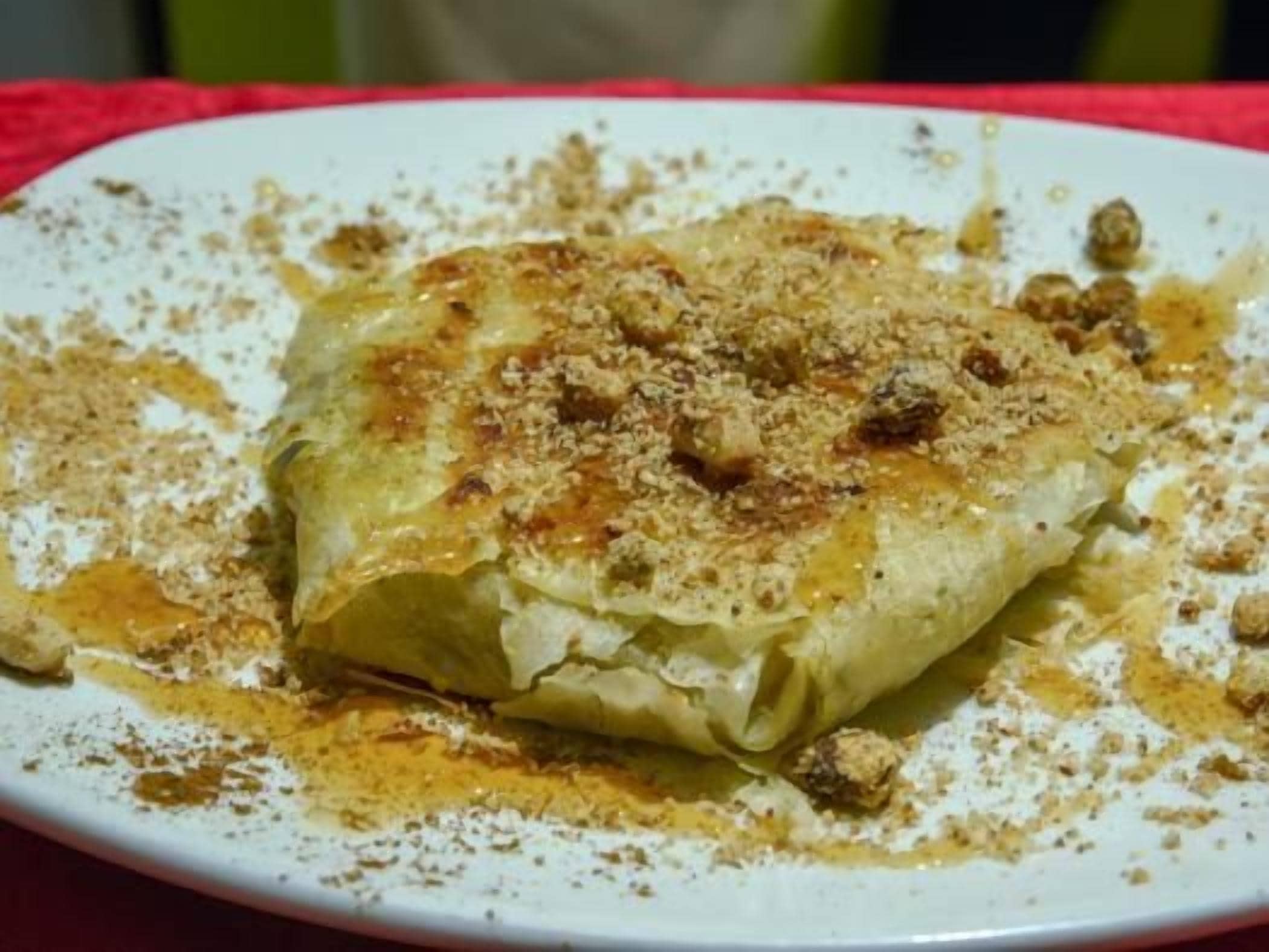 A plate with a food item, possibly a pastry, sprinkled with a brown powder, likely cinnamon, on a white plate.