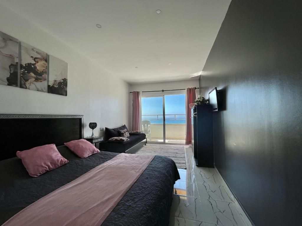A modern hotel room with a large bed, a flat-screen TV, and a balcony with a view.