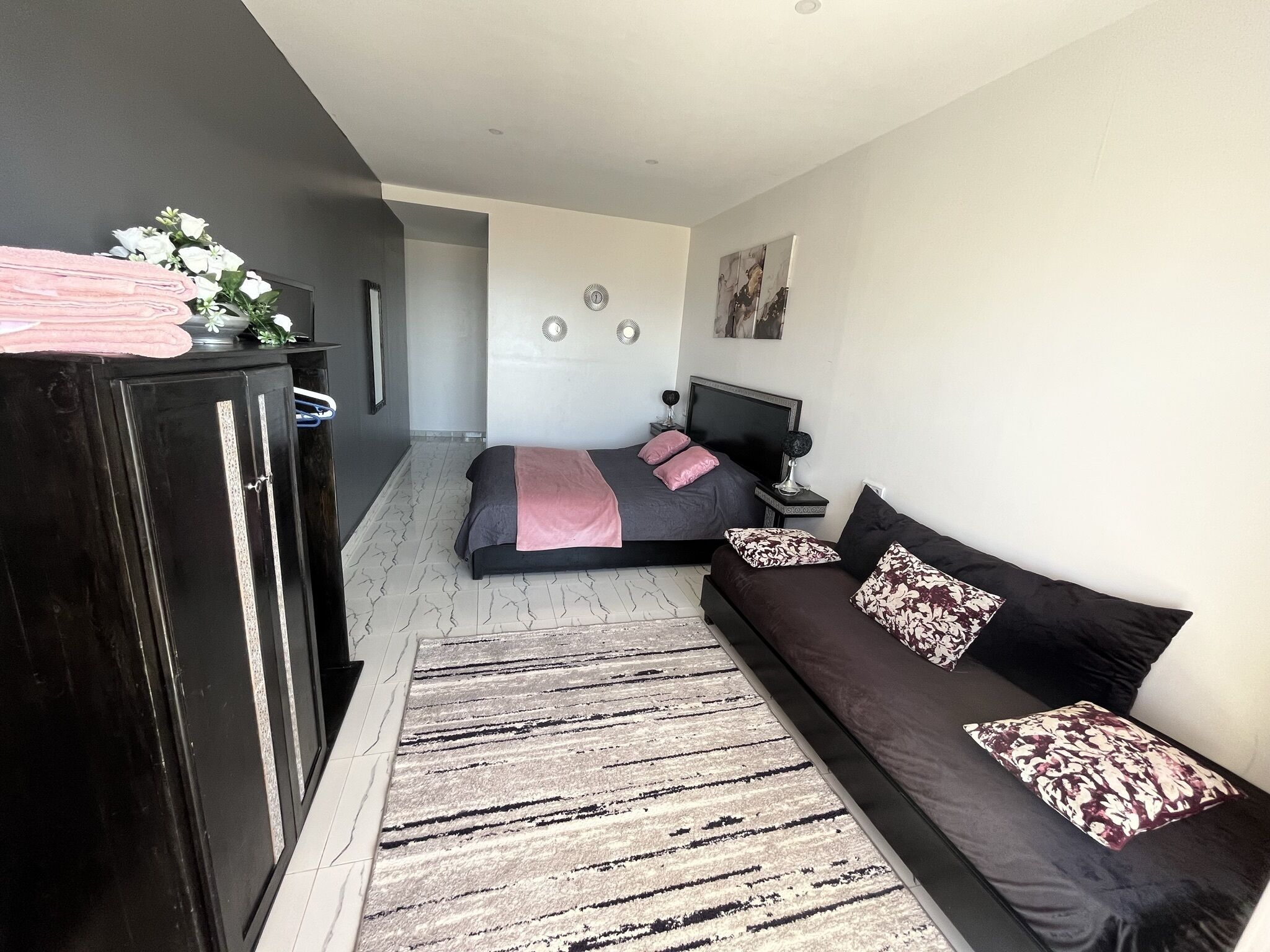 Une chambre à coucher moderne avec un lit, un canapé, une commode et un tapis.