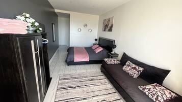 Une chambre à coucher moderne avec un lit, un canapé, une commode et un tapis.
