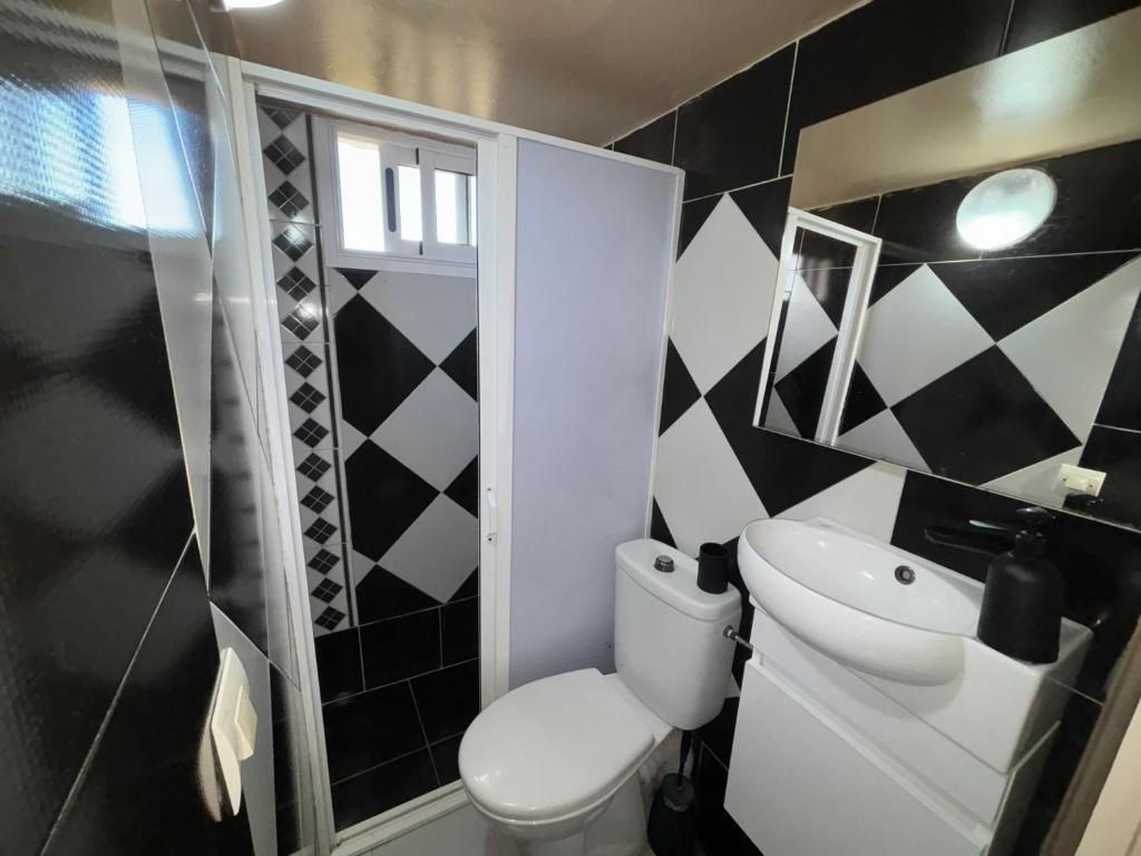 A bathroom with a toilet, sink, and mirror.