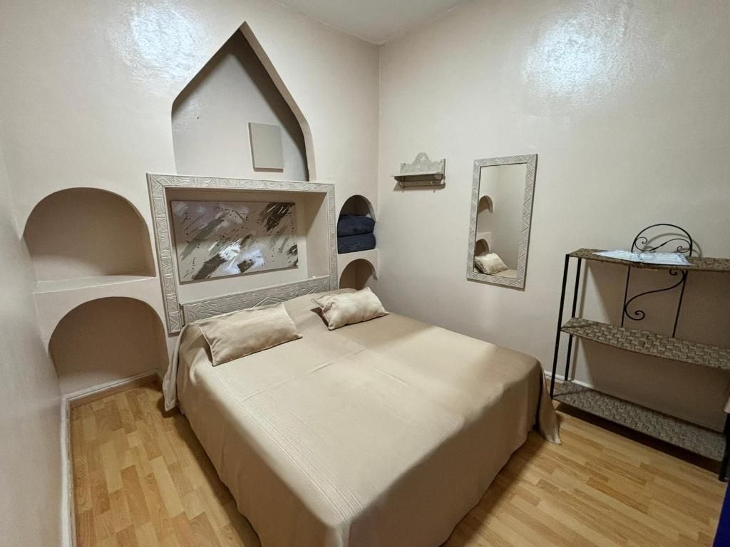 Un dormitorio con una cama, cómoda, espejo y un arco decorativo en la pared.