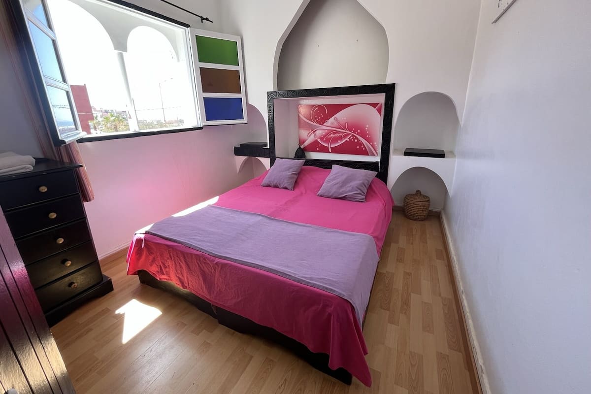 A bedroom with a bed, dresser, window, and decorative wall.