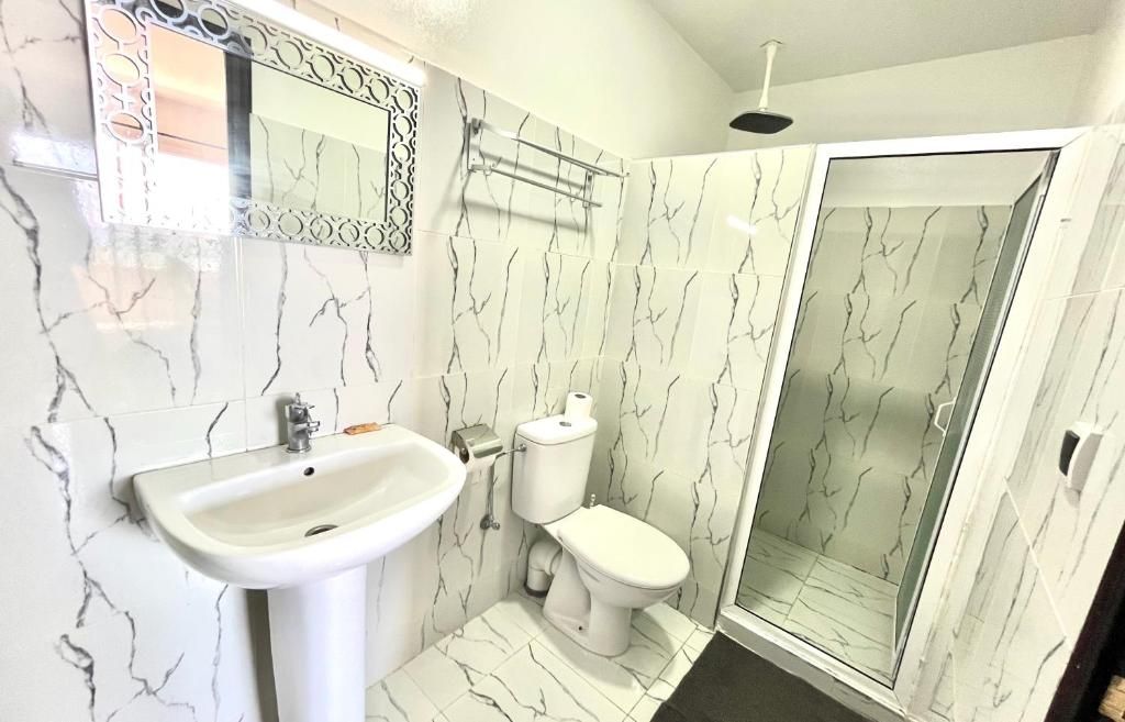 A bathroom with a white sink, toilet, and shower enclosure.