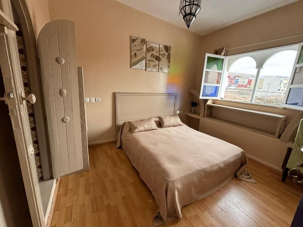 A bedroom with a bed, a wardrobe, a window with a view, and a ceiling light.