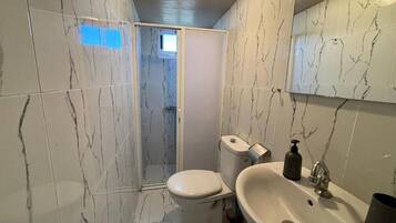 Un baño con inodoro, lavamanos y espejo.