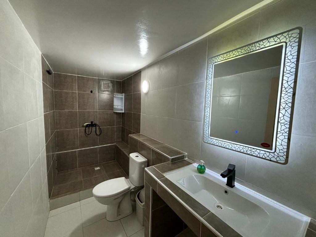 Un baño moderno con inodoro, lavamanos y zona de ducha.