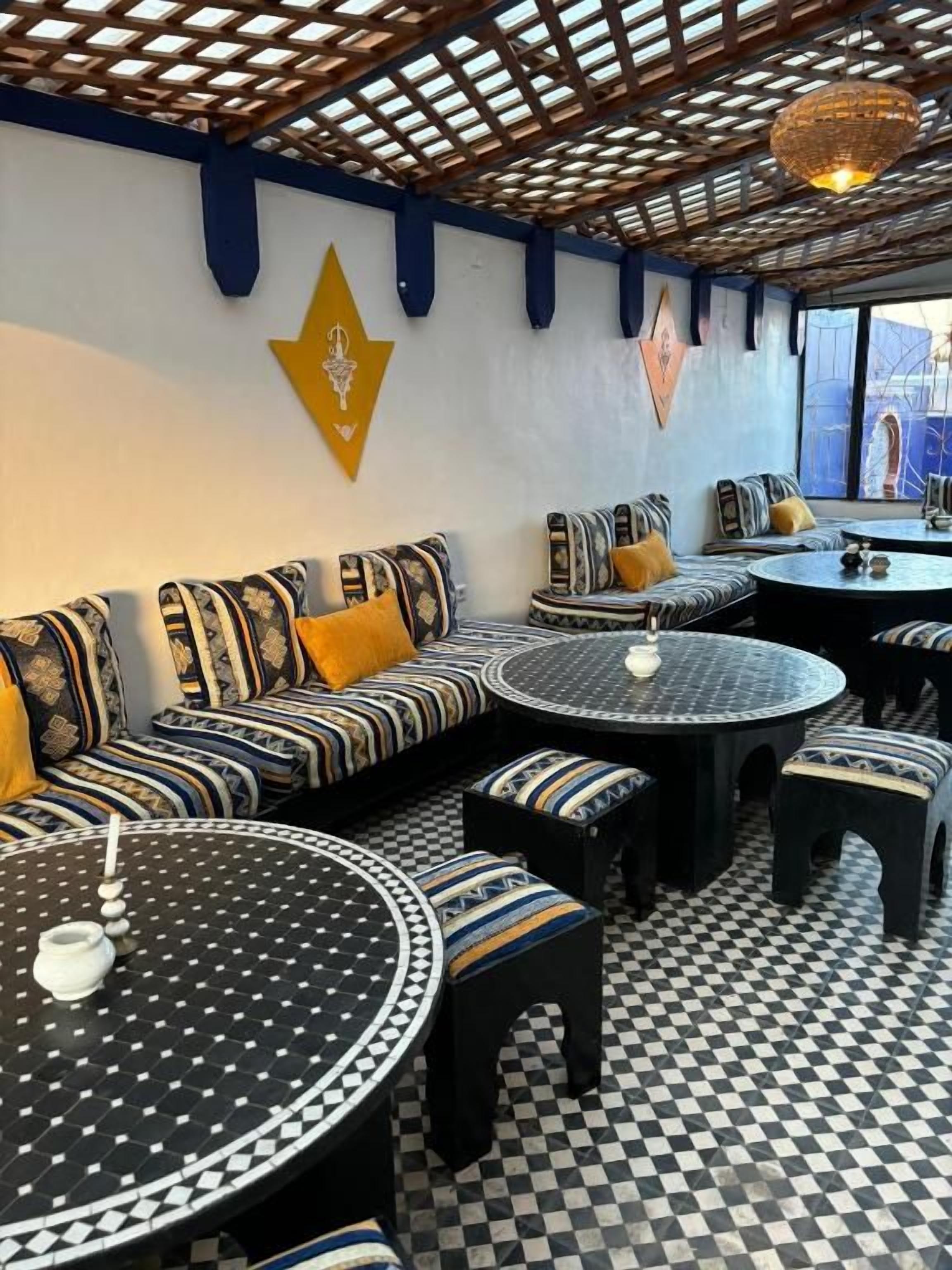 A café with patterned sofas and round tables, a checkered floor, and decorative wall art.