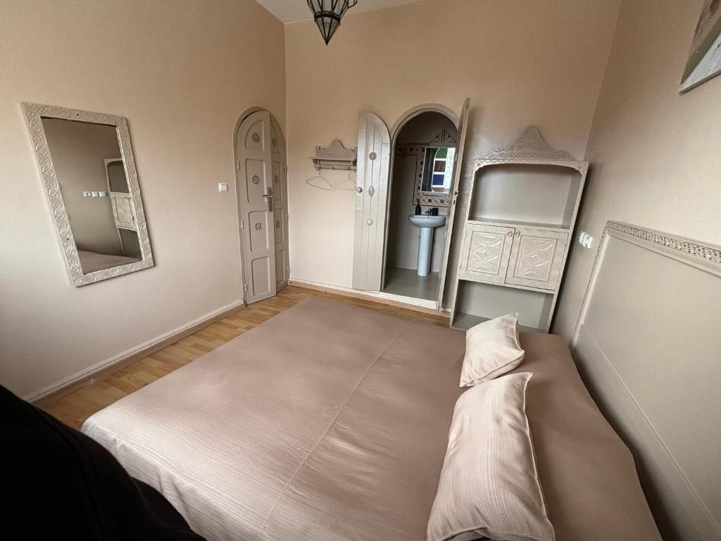 Een slaapkamer met een groot bed, een kledingkast, een spiegel en een deur naar een badkamer.