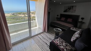 A bedroom with a bed, a small table, and a view of the sea. - Riad Dar Naima Imsouane (Imsouane)
