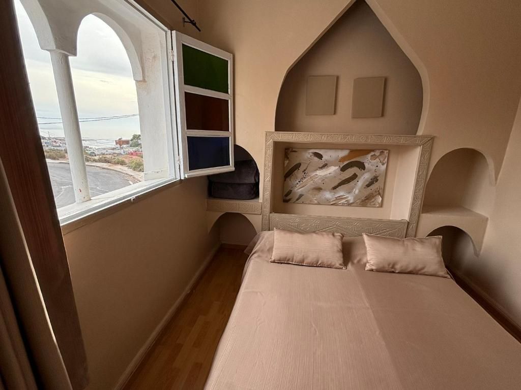 Un dormitorio con una cama, un ventanal y una repisa en la pared.