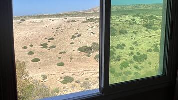 Una habitación con un ventanal amplio que ofrece vistas a un paisaje árido y rocoso con vegetación escasa.