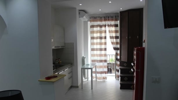 A modern kitchen with white cabinets, a dining table, and a striped curtain. - B&B Xenia (Palermo)