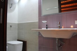 Un baño con un inodoro blanco, un lavabo con espejo y un perchero para toallas.