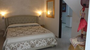 A bedroom with a large bed, two wall-mounted lights, a mirror, and a mannequin with a red dress. - B&B Xenia (Palermo)