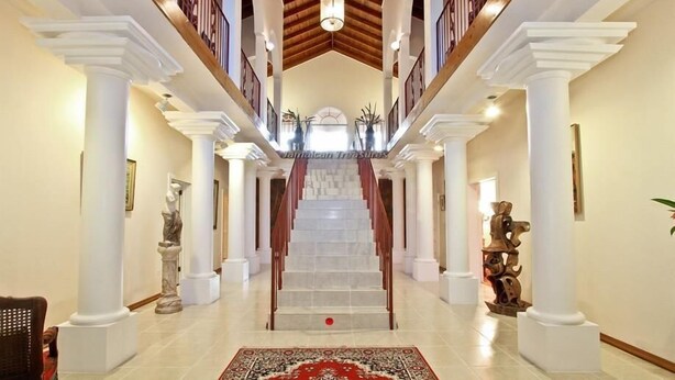 Una gran escalera con columnas blancas y una alfombra roja que lleva a un balcón.