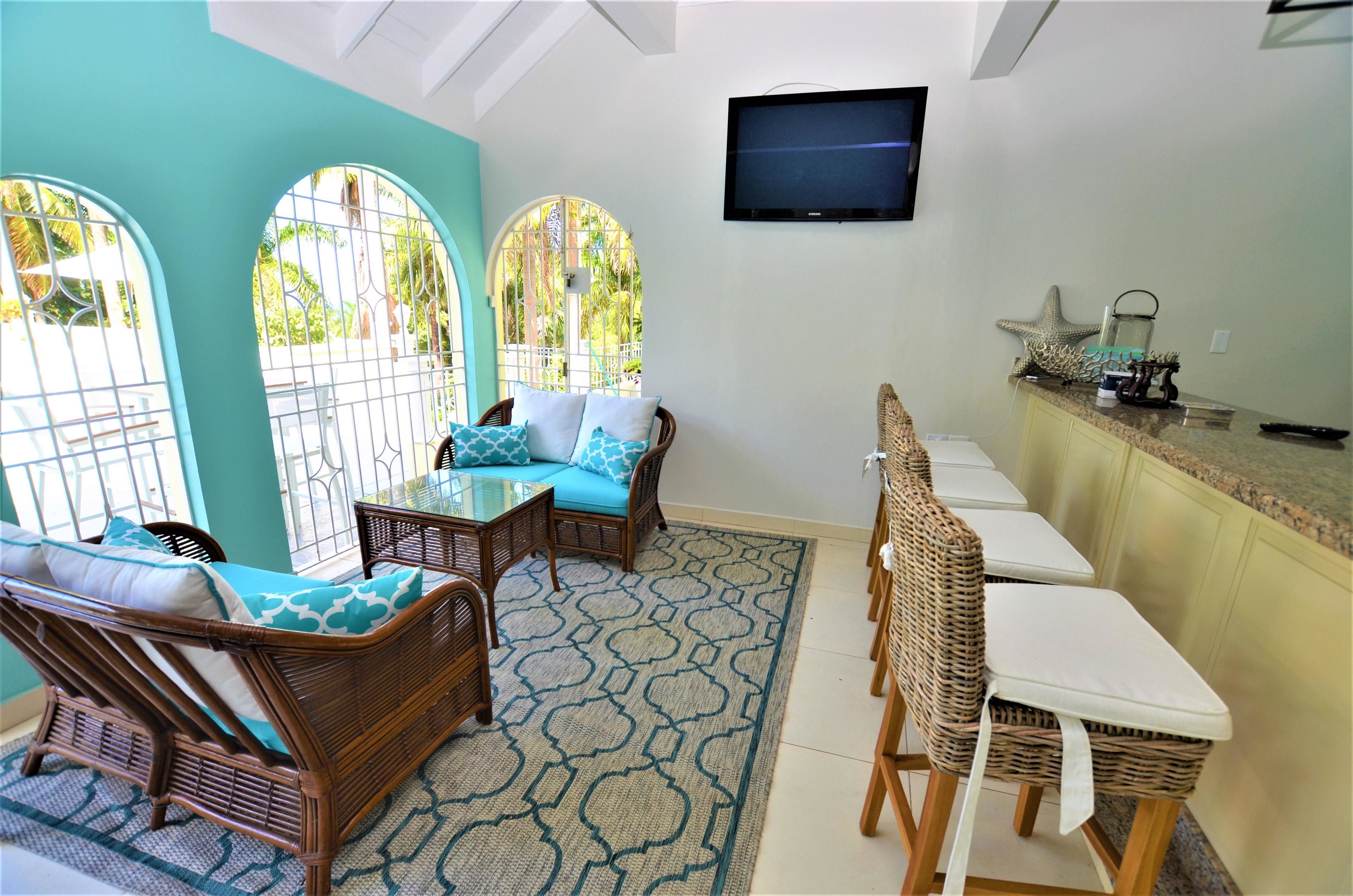 Habitación con comedor, un conjunto de sofás, un televisor montado en la pared y vistas a través de una ventana.