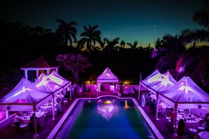 A poolside area with multiple tents and tables, surrounded by palm trees and a clear sky. - Summerhill, 8BR by Jamaican Treasures (Montego Bay)