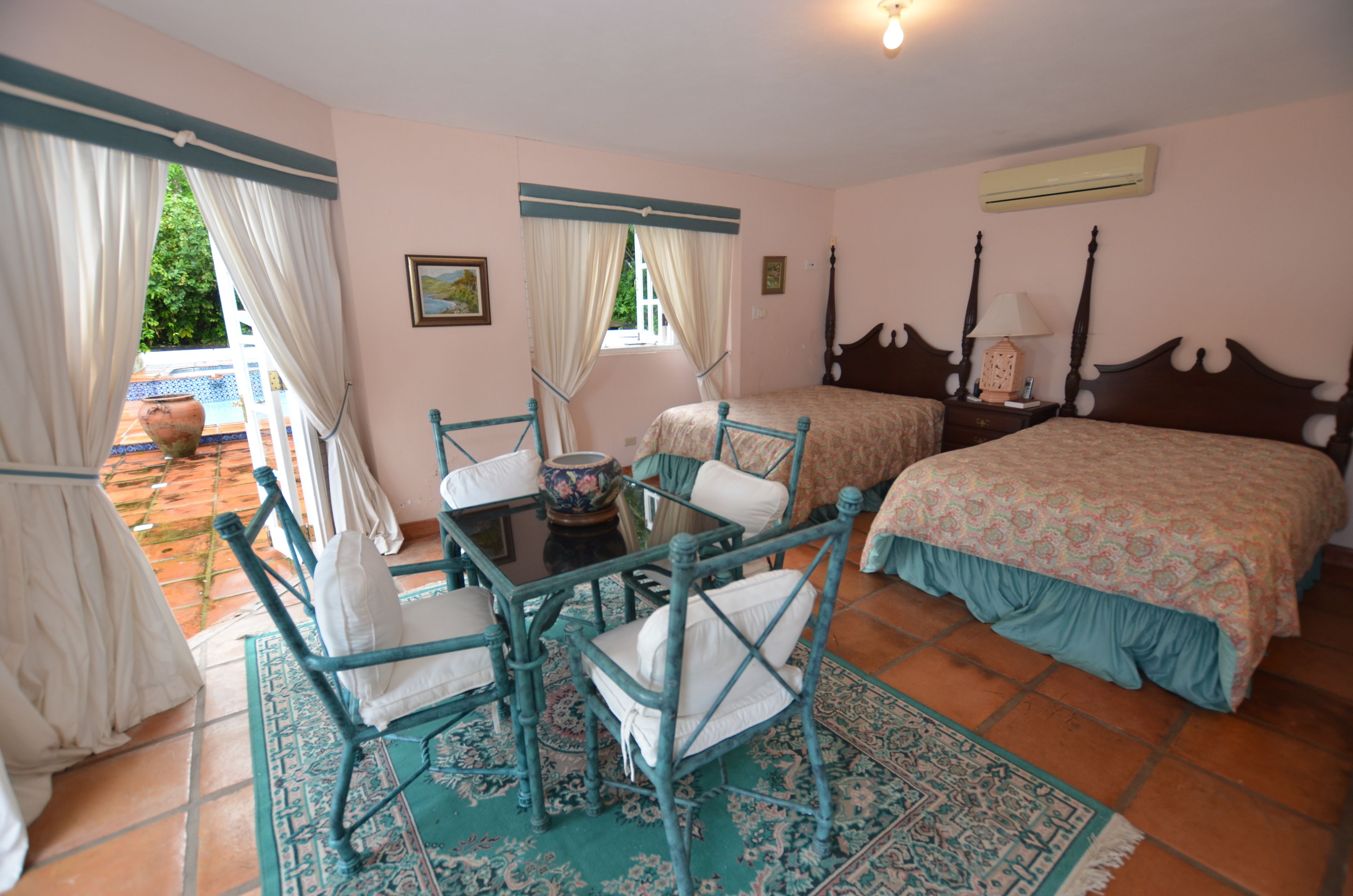 A bedroom with a bed, two chairs, a table, and a window with curtains.