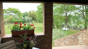 A covered outdoor area with a view of a garden and a white outdoor seating area. - Podere Agrituristico Luchiano (Amelia)