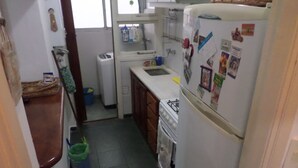 A compact kitchen with a refrigerator, stove, and sink. - Departamento MDQ Colon by EF (Mar del Plata)