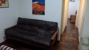 A living room with a dark leather sofa, a wooden coffee table, and a colorful painting on the wall. - Departamento MDQ Colon by EF (Mar del Plata)