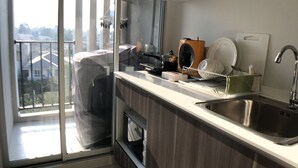 Une cuisine moderne équipée d’un four encastré, d’un évier et d’une fenêtre donnant sur un balcon.
