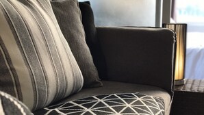 Un canapé agrémenté de coussins à rayures et à motifs géométriques, une lampe et une fenêtre en arrière-plan.