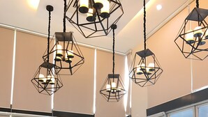 Un intérieur moderne avec un canapé, des suspensions lumineuses aux formes géométriques et de grandes fenêtres.