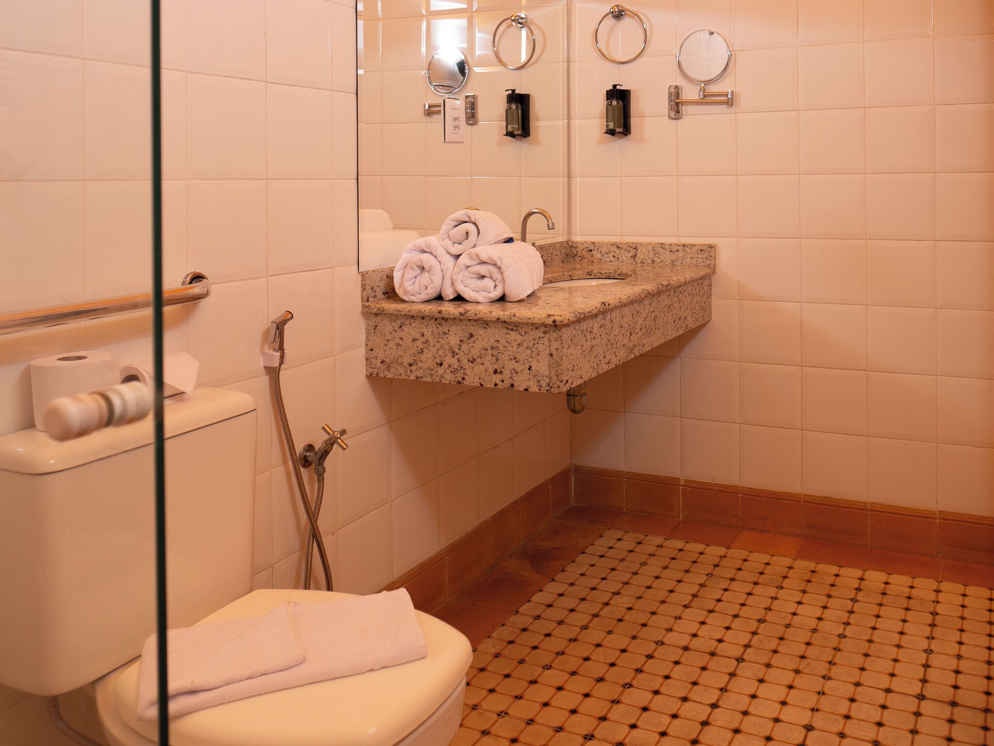 Un baño con inodoro, lavabo y ducha. Hay toallas sobre el inodoro y el lavabo.