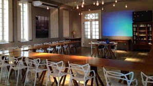 Una sala de conferencias con una larga mesa y sillas, una pantalla de proyector y una estantería.
