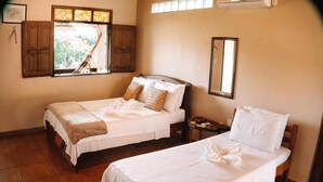 A hotel room with two single beds, a wooden wardrobe, a window with curtains, a mirror, and a small table. - Amazônia ParkSuítes (Novo Airão)
