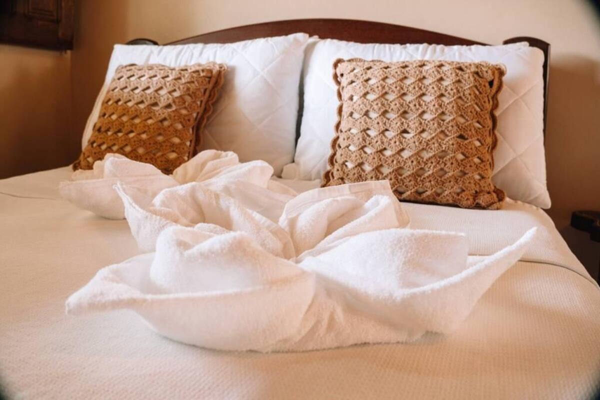 Un lit avec deux oreillers à texture, une couverture blanche et une serviette blanche.