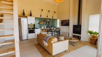 Une cuisine moderne équipée d’un réfrigérateur, d’un four et d’un évier. On y trouve également un coin repas avec une table et des chaises. Un canapé est installé dans l’espace salon.
