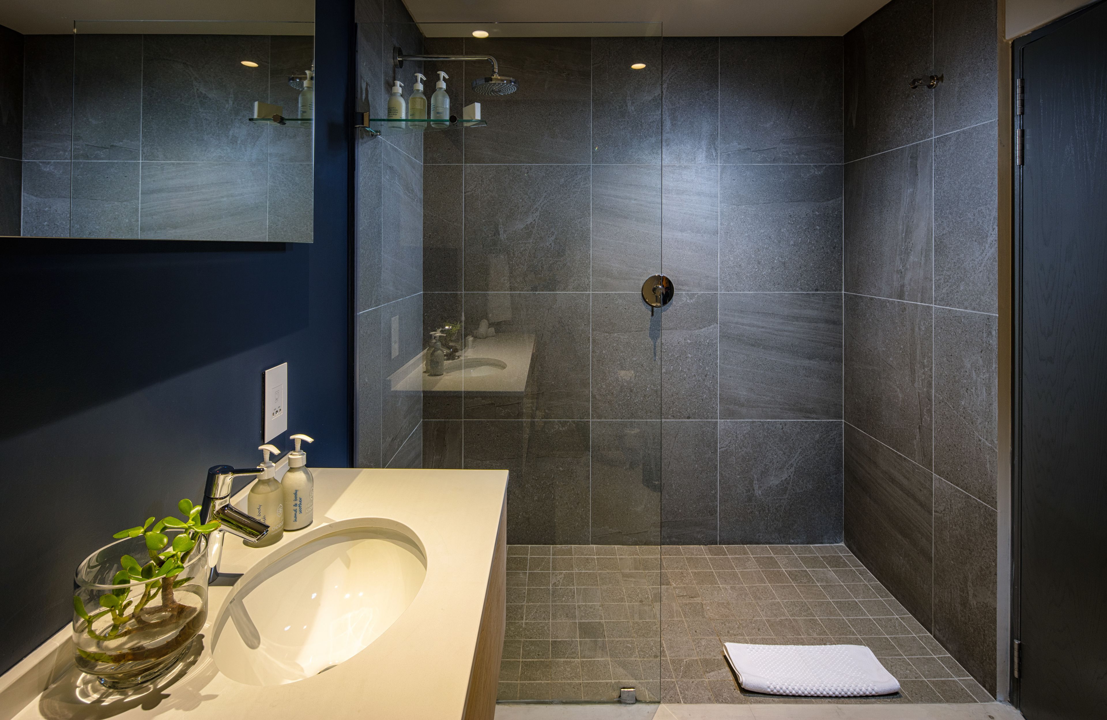 Ein modernes Badezimmer mit einem Glaswaschbecken, einer Dusche und einem großen Spiegel.