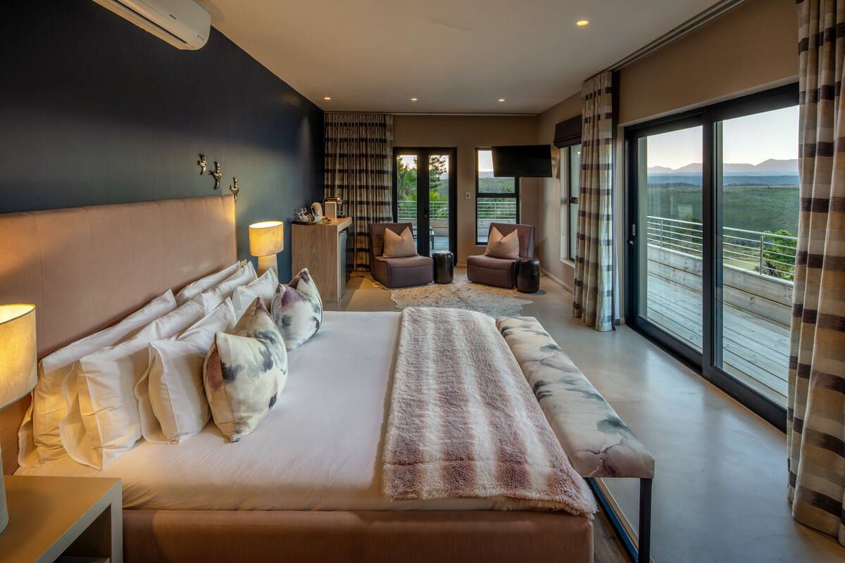 Un dormitorio moderno con una cama grande, un escritorio y vistas al exterior.