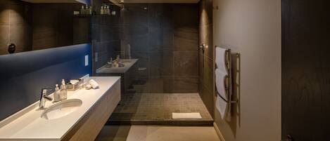 Een moderne badkamer met twee wastafels, een douche en een grote spiegel.