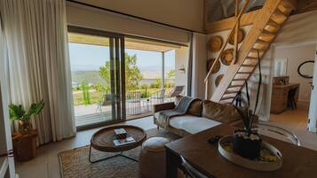 A spacious living area with a large sliding glass door leading to an outdoor patio, a wooden staircase, and a cozy seating arrangement.