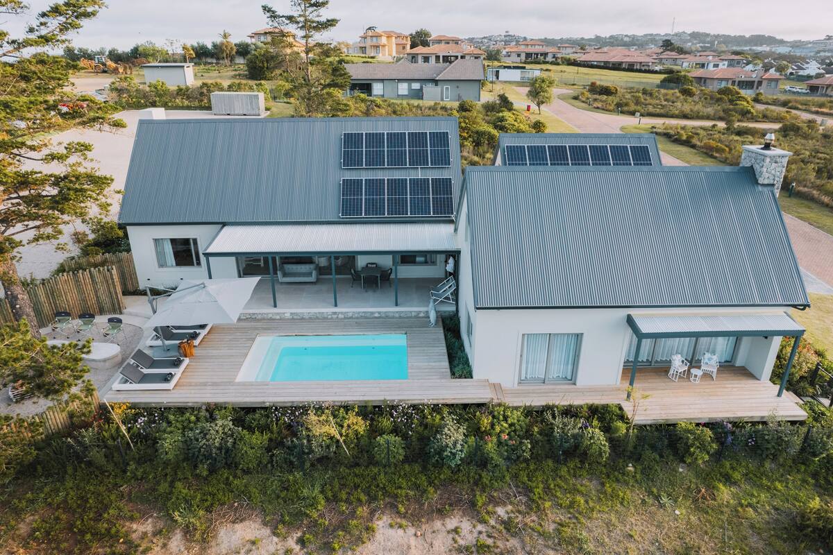 Una casa moderna con piscina, paneles solares y una terraza.