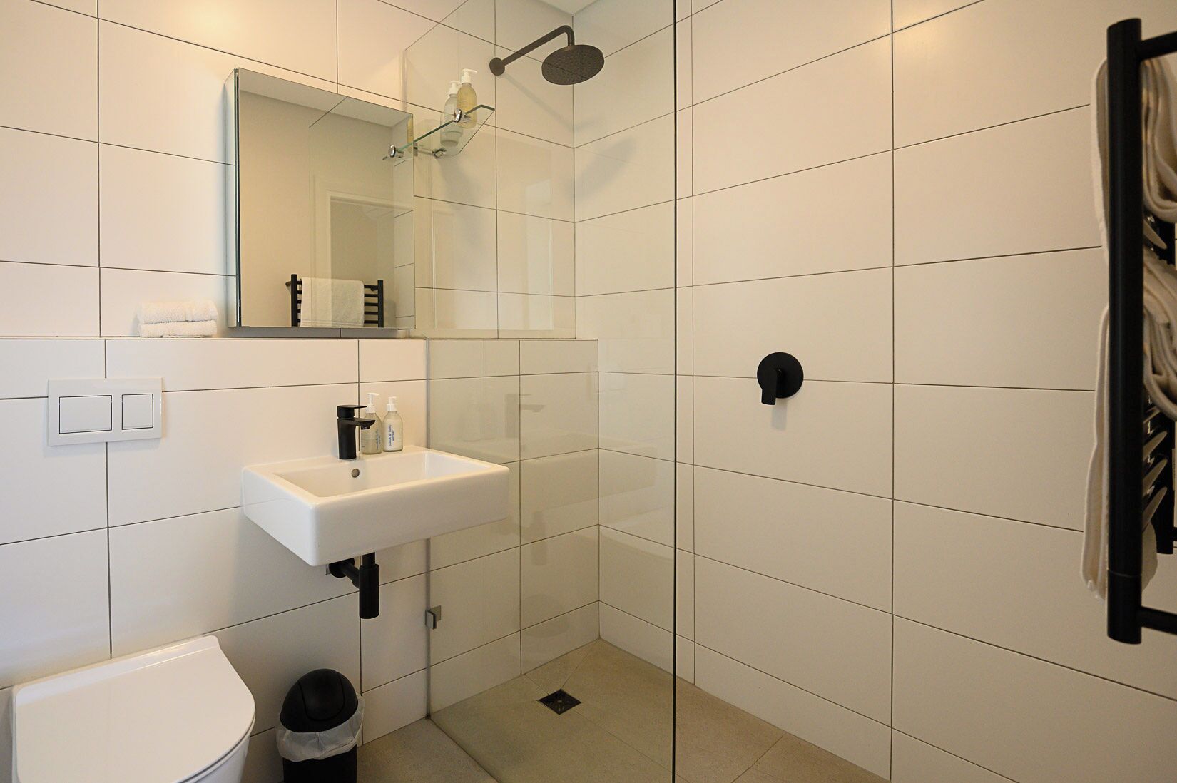A modern bathroom with a white sink, mirror, and shower.