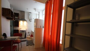 Una cocina compacta con comedor, refrigerador y un tapete a cuadros.